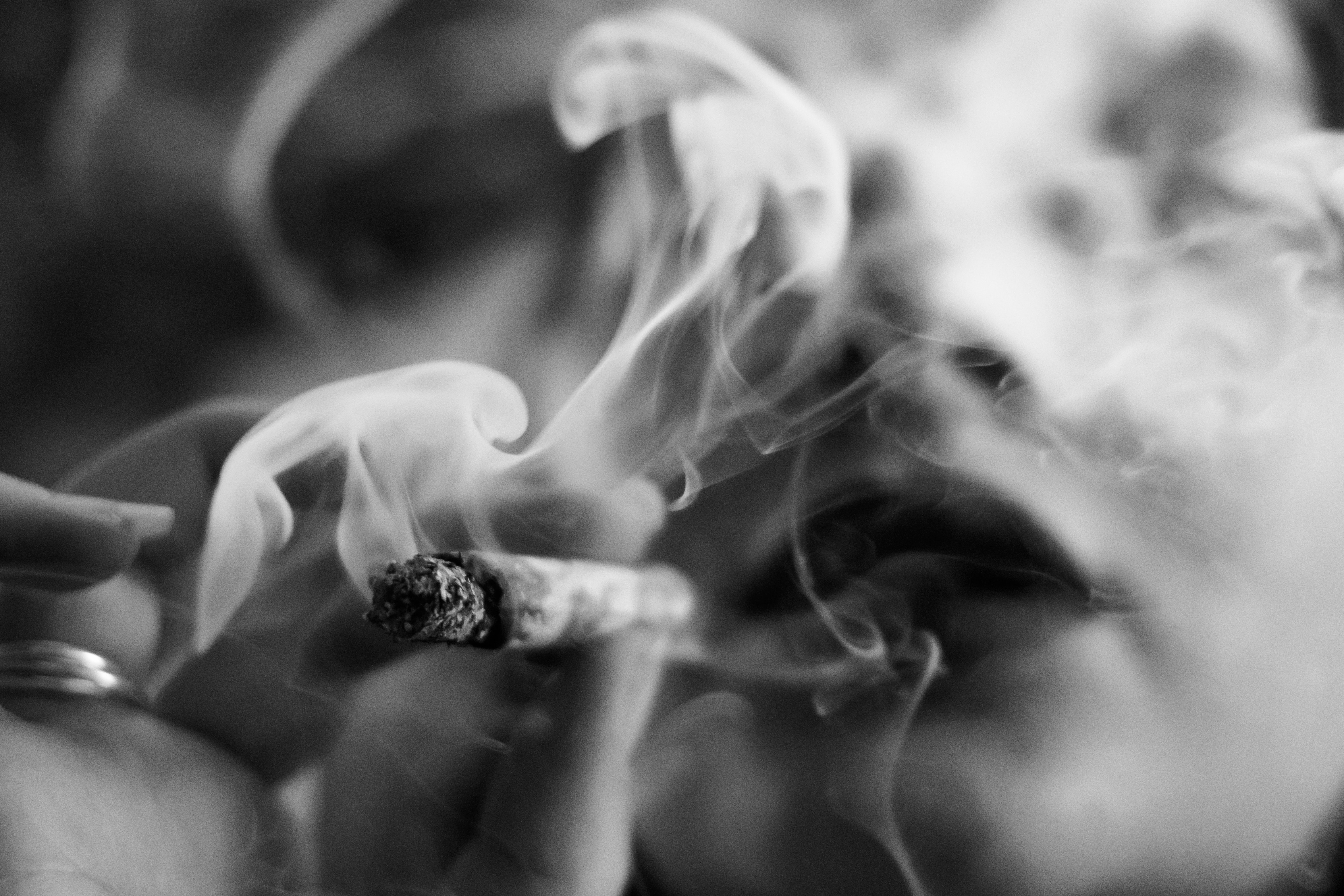 Emotive image of woman smoking, close up, greyscale, film grain.