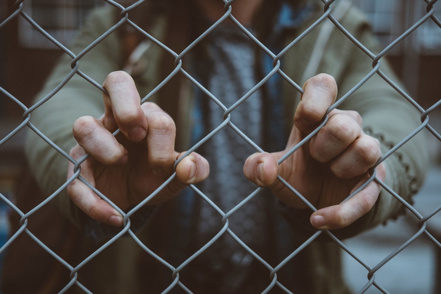 Not much of a bargain - man gripping wire fence. Photo by Mitch Lensink, Unsplash